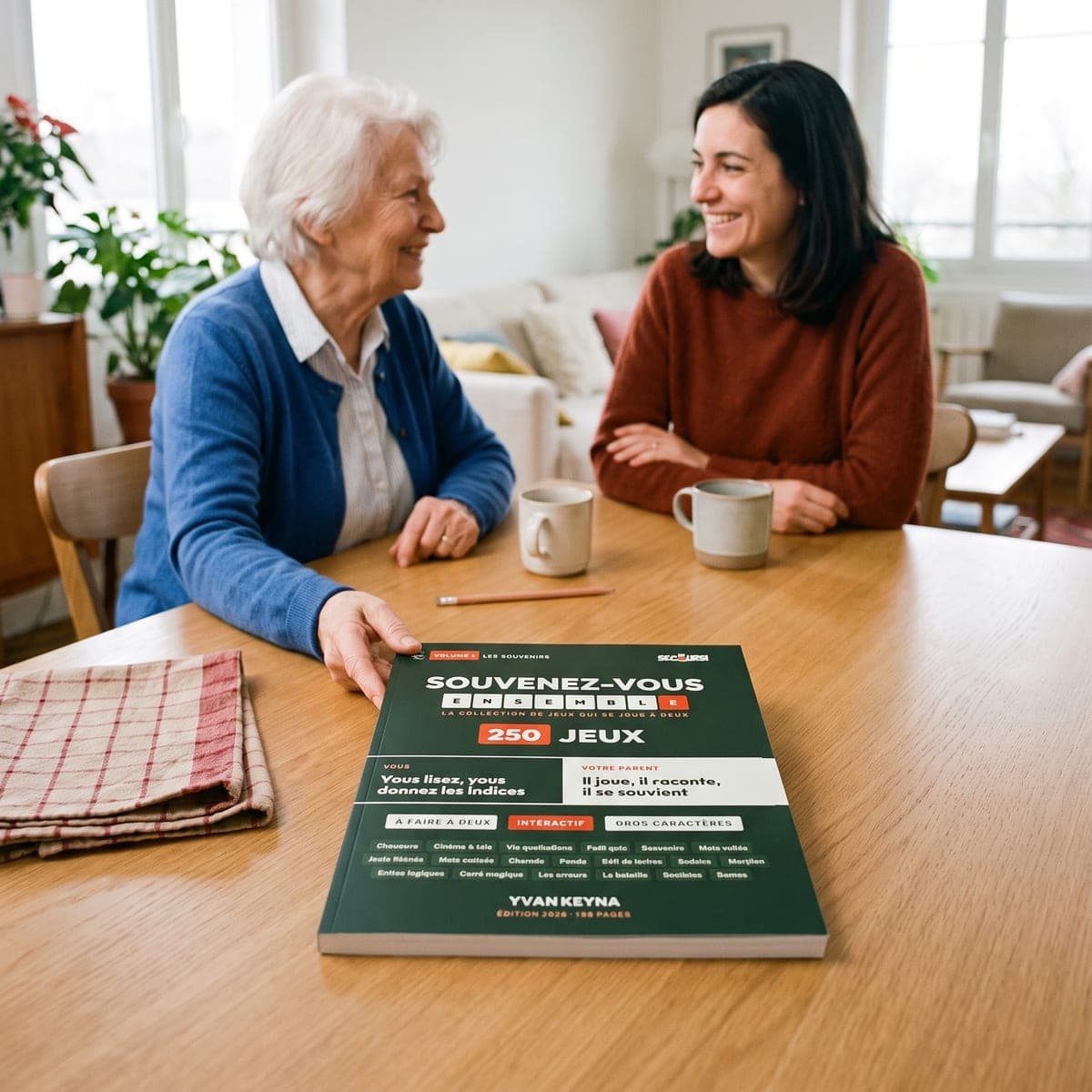 Uma mãe idosa e a filha riem juntas à mesa, com o livro «Recordemos juntos» à frente delas